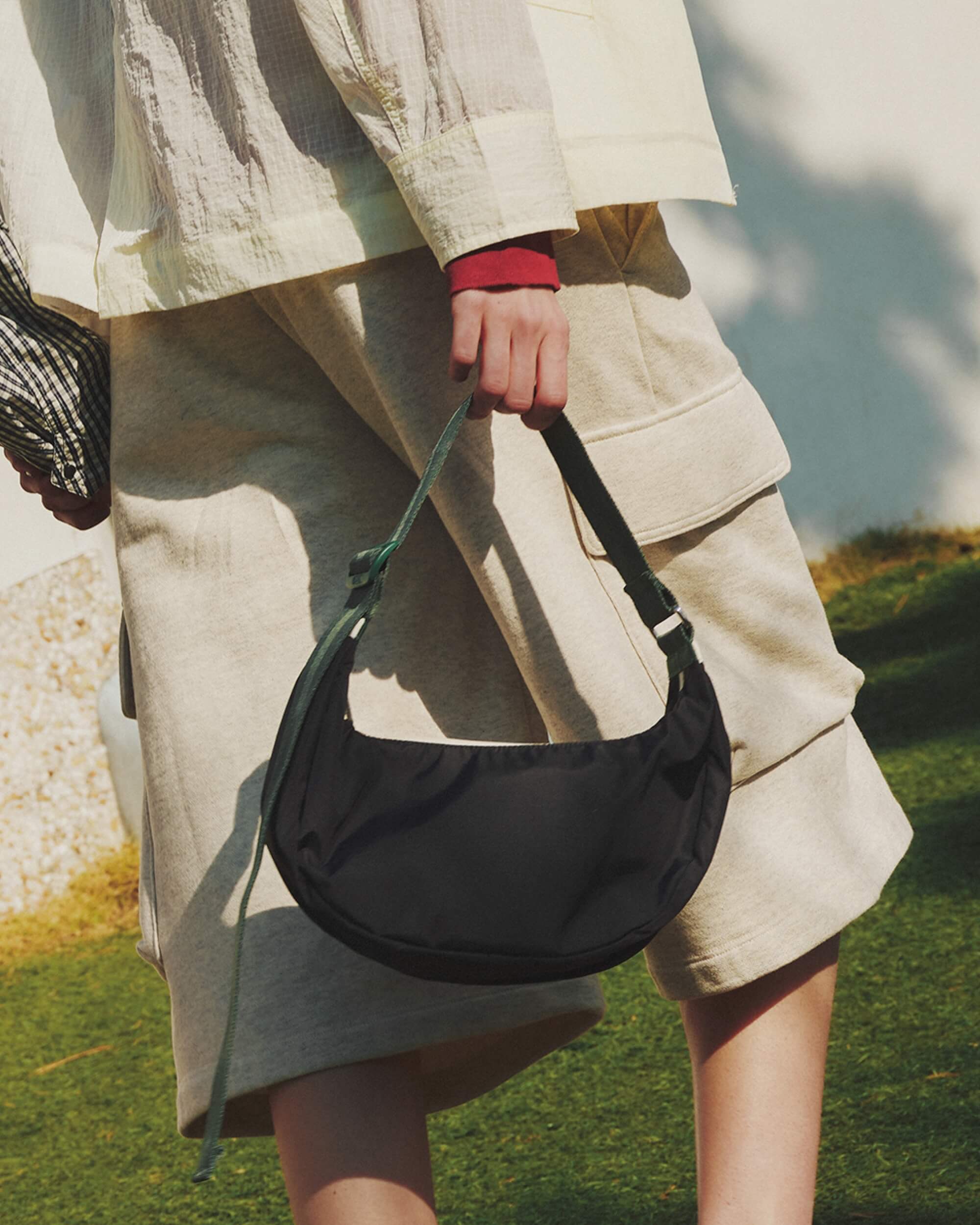 MED HAMMOCK ADJ BAG ディープシー/ボトルグリーンウェビングを持った女性モデルの画像