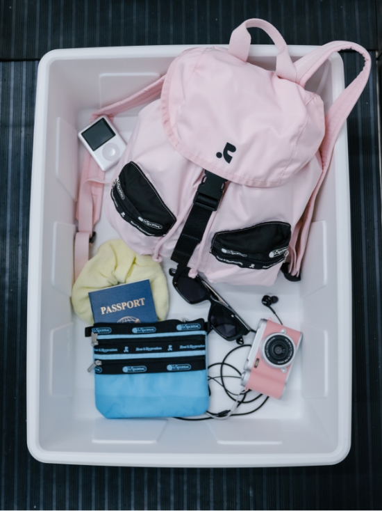 トレイにまとめられたピンクのリュックと旅行小物